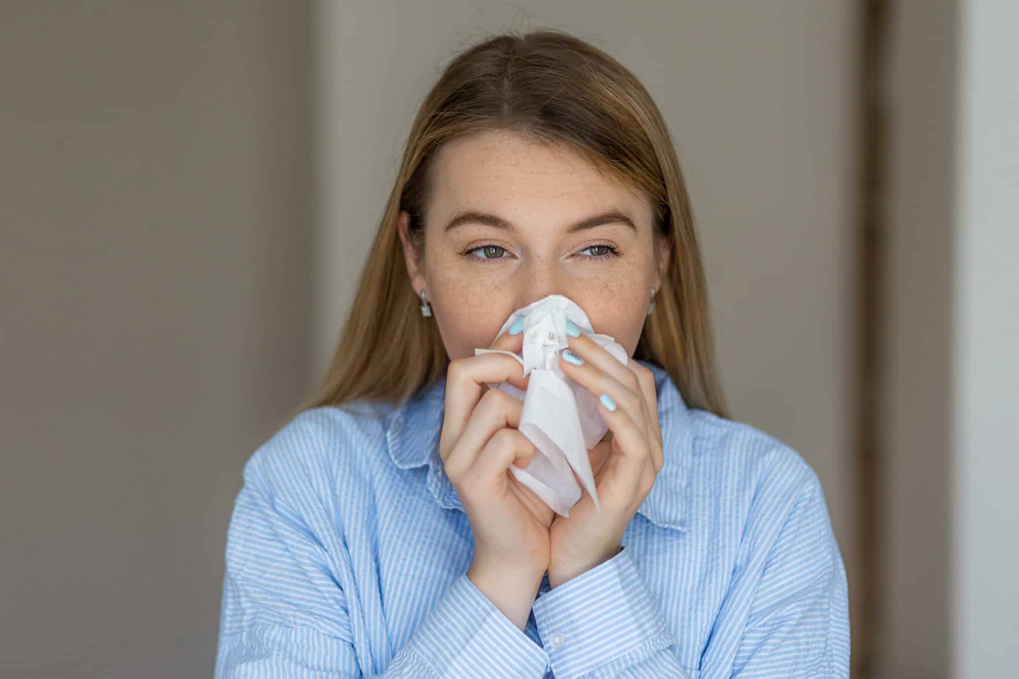 Woman sneezing into tissue because of allergies, Mold from Plumbing Leaks.